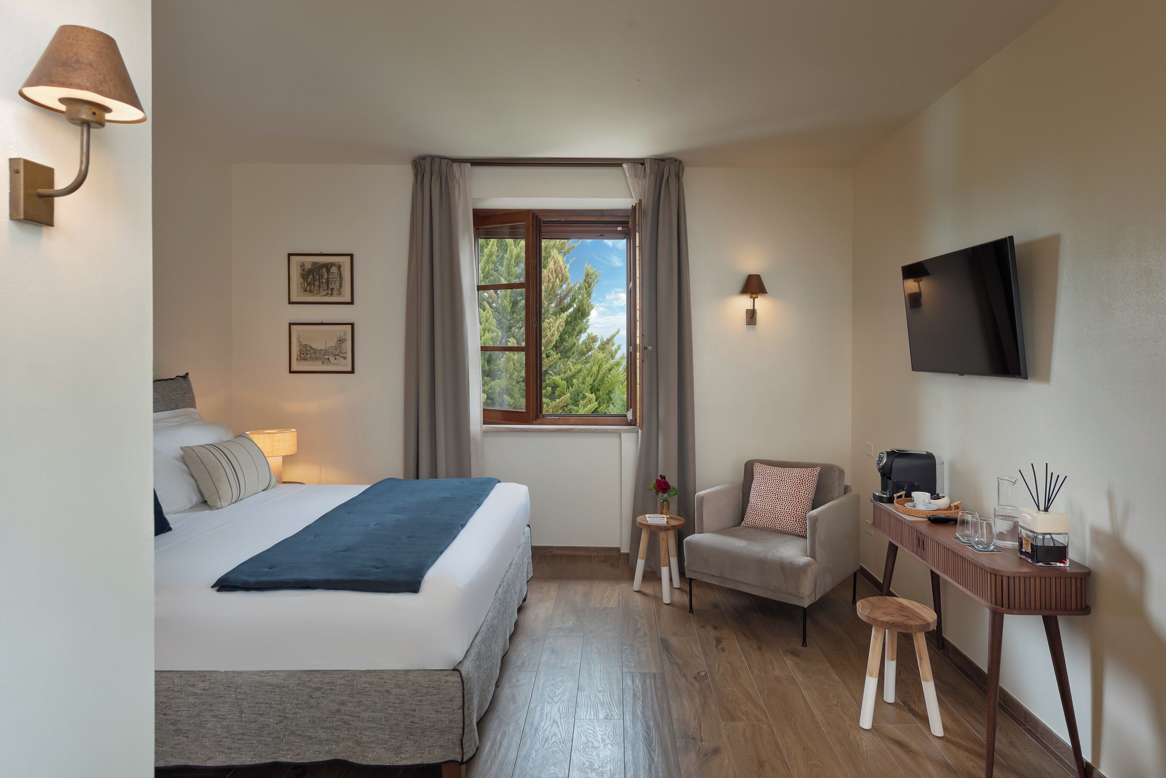 Ein modernes Hotelzimmer mit einem Bett, einem Schreibtisch, einem Sessel, einem Fernseher und einem Fenster mit Vorhängen.