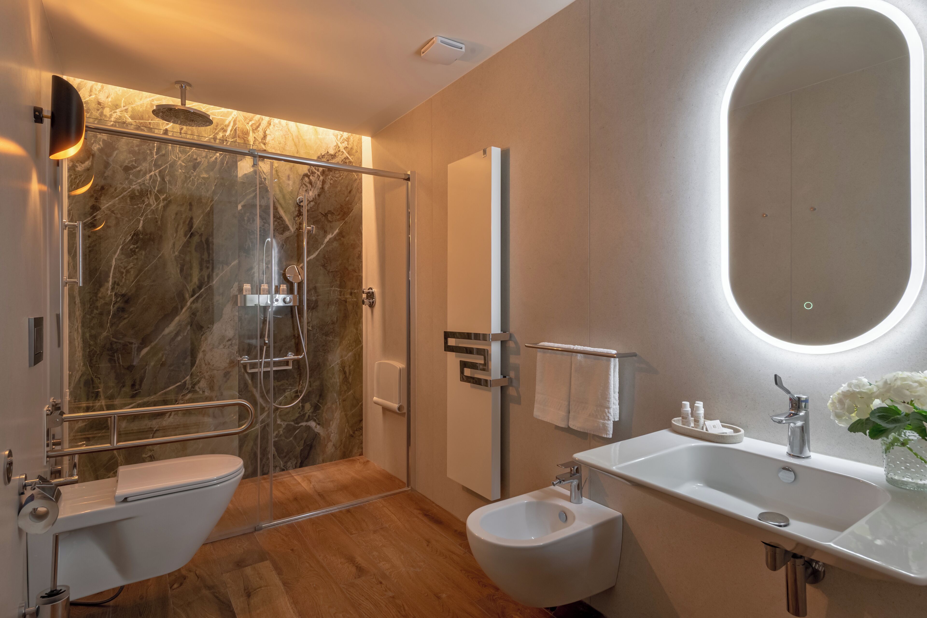 Ein modernes Badezimmer mit einer gläsernen Duschkabine, einem weißen Waschbecken und einem Bidet.