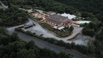 Vista aérea de una propiedad con un edificio central, piscina y vegetación circundante.