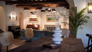 Uma área de refeições com mesa de madeira, cadeiras e um vaso com flores brancas.