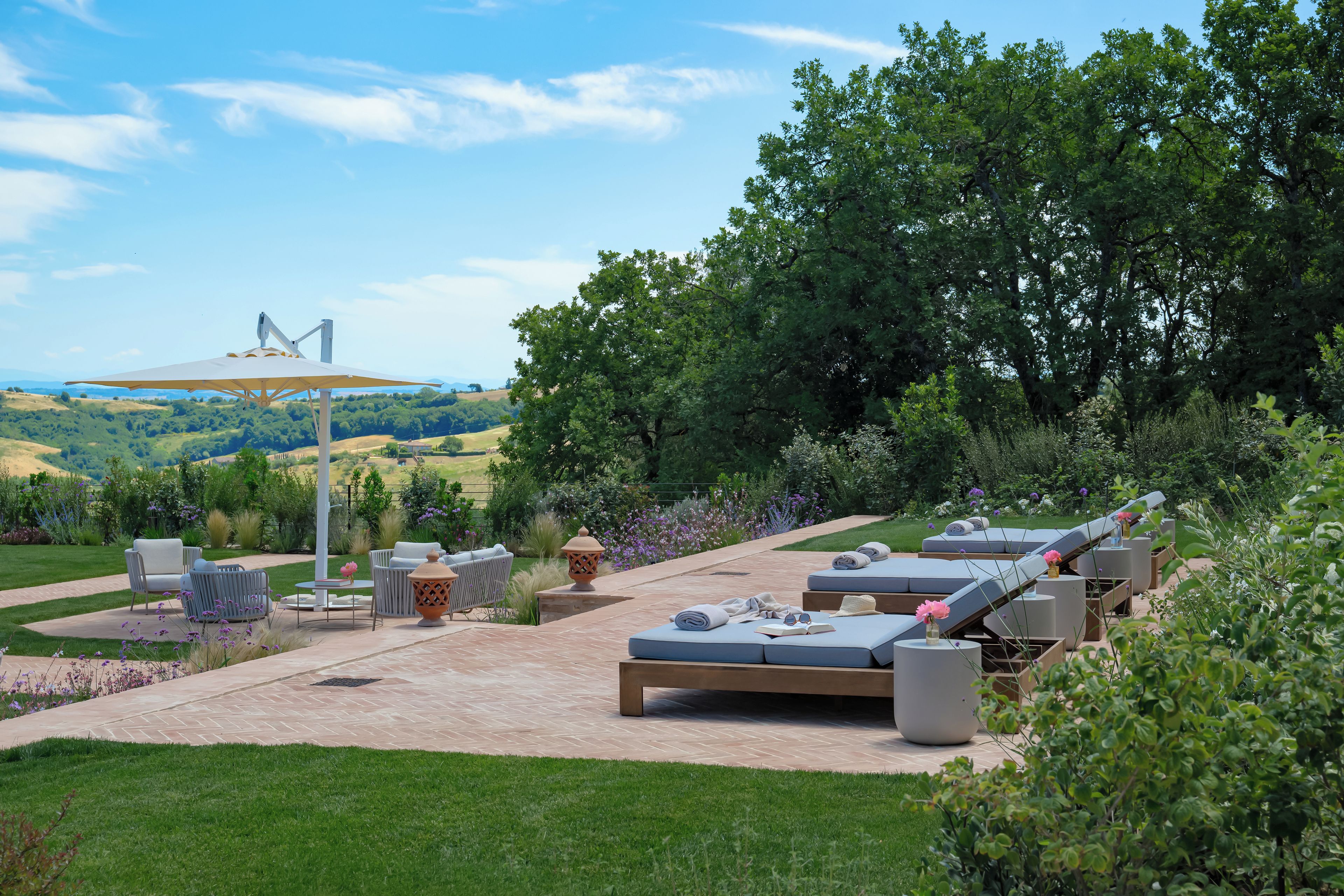 Un espacio al aire libre con mobiliario exterior, un pérgola y una vista de un puente a lo lejos.