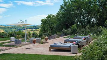 Un espacio al aire libre con mobiliario exterior, un pérgola y una vista de un puente a lo lejos.