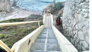 Una escalera de piedra que conduce a una zona costera con vista al océano.