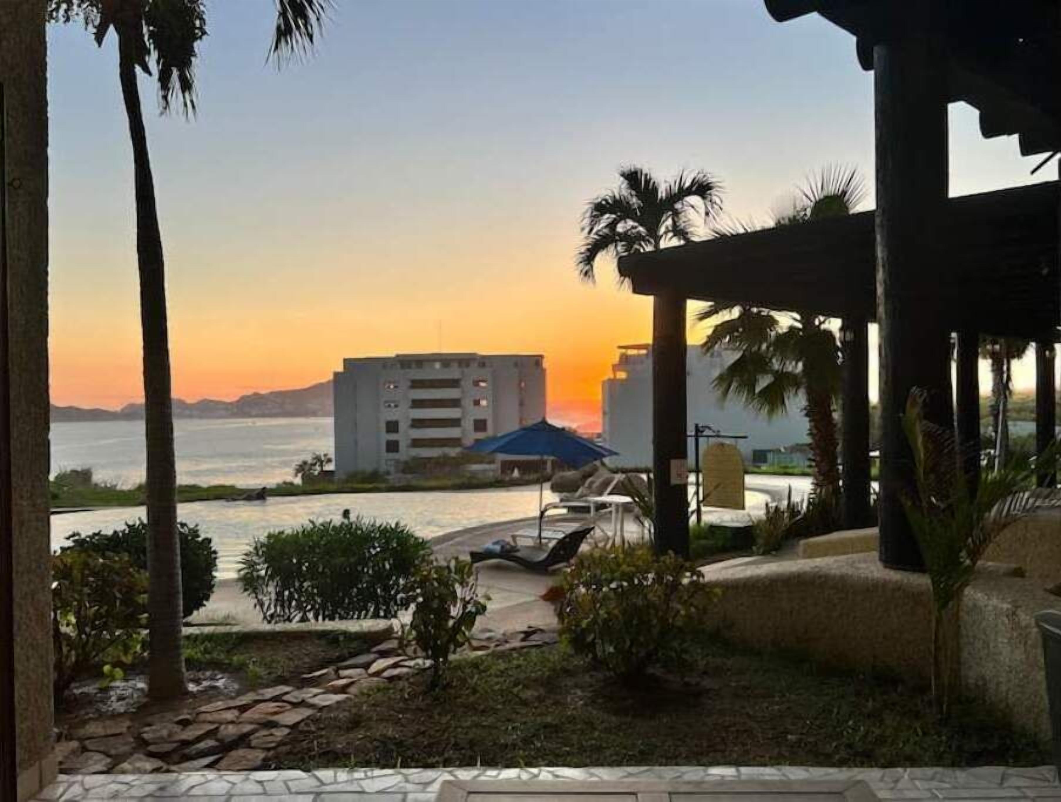 Vista de um edifício com telhado azul e área de piscina com espreguiçadeiras.