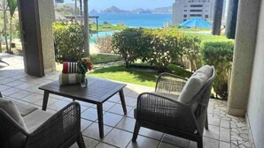 Un patio con una mesa y dos sillas, con vista a una piscina y al mar.