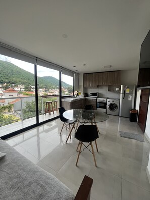 A modern kitchen with a dining area, large windows, and a view of a hillside. - Cozy central apartment, perfect for getaways (Salta)