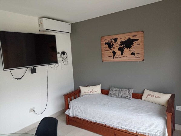 A bedroom with a bed, a TV mounted on the wall, and a world map on the wall. - Cozy central apartment, perfect for getaways (Salta)