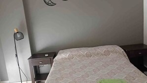 A bedroom with a bed, a nightstand, a lamp, and a wall with moon phase decorations. - Cozy central apartment, perfect for getaways (Salta)