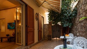 Un patio con una mesa lista para comer, una botella de vino y una silla.