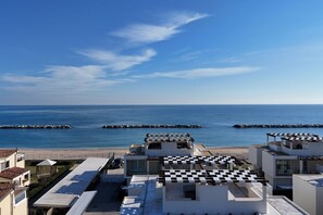 A coastal hotel with modern architecture, a beach view, and a checkered roof design. - P020 - Porto Recanati, new three-room apartment with garden (Porto Recanati)