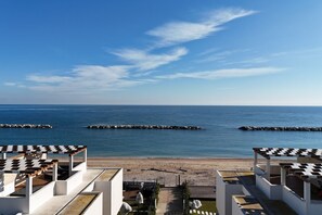 A beach view with a clear sky, a sandy shore, and a series of white and black checkered structures. - P020 - Porto Recanati, new three-room apartment with garden (Porto Recanati)
