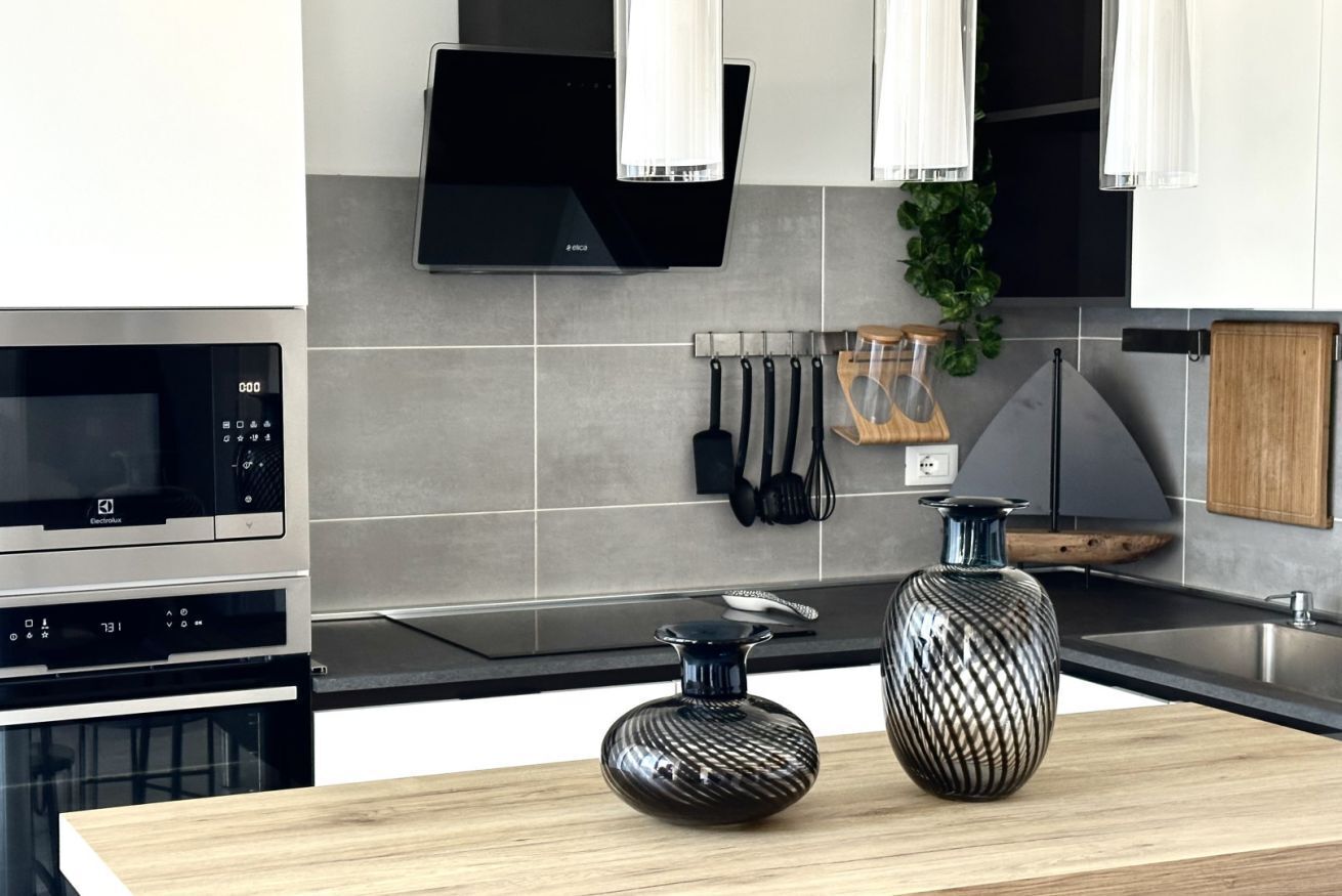 A modern kitchen with a microwave, oven, and a wooden countertop.