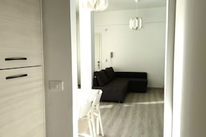 A modern interior with a wooden wardrobe, a black sofa, a white table, and a ceiling light fixture.