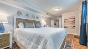 Une chambre à coucher avec un grand lit, des tables de chevet, un tapis et des œuvres d’art accrochées aux murs.