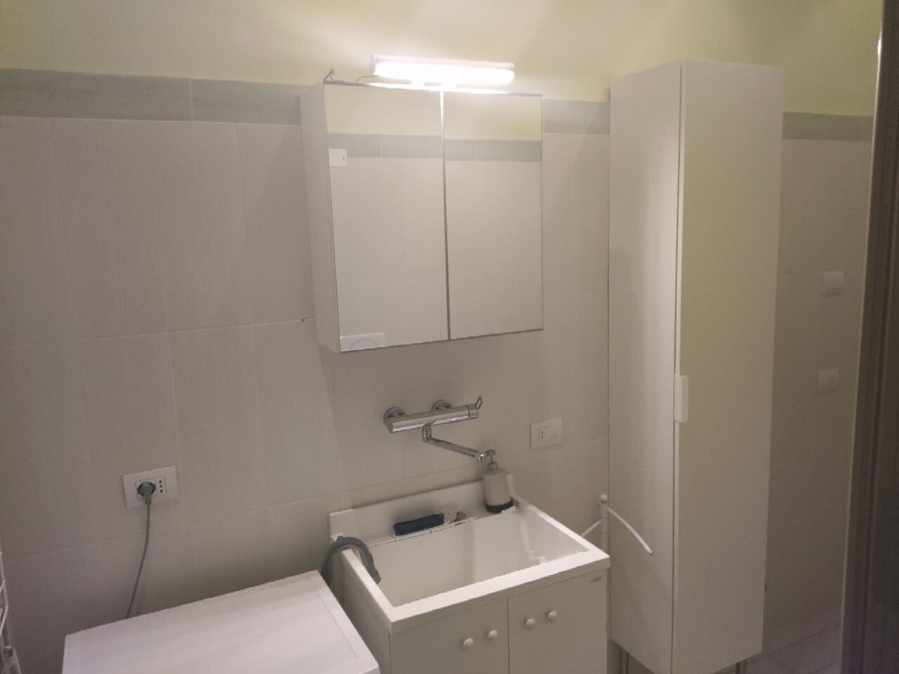 A small, basic bathroom with a sink, mirror, and cabinet.