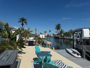 A waterfront patio with outdoor seating, a boat docked on the water, and a clear view of the marina.