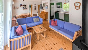Una sala de estar acogedora con sofás azules, una mesa de centro de madera y un comedor con mesa y sillas de madera.