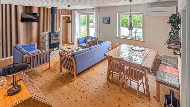 Un espacio de estar acogedor con chimenea, sofá azul, mesa de comedor de madera y una zona de cocina.