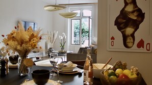 A dining area with a table set for two, a vase of flowers, and a painting of the Mona Lisa on the wall.