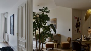 A modern living room with a large potted plant, a dining area with a table and chairs, and a painting of the Mona Lisa on the wall.