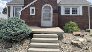 A two-story brick house with a white front door, a small window, and a chimney. - Cozy and relaxing (Linton)