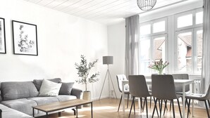 Un salon moderne avec un canapé gris, une table basse en bois et un coin repas comprenant des chaises et une table.