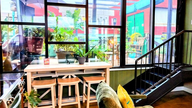 Una cocina con un ventanal grande, taburetes de madera y una mesa.