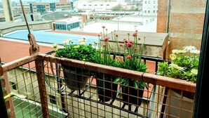 Un balcón con plantas en macetas y vista a un paisaje urbano.