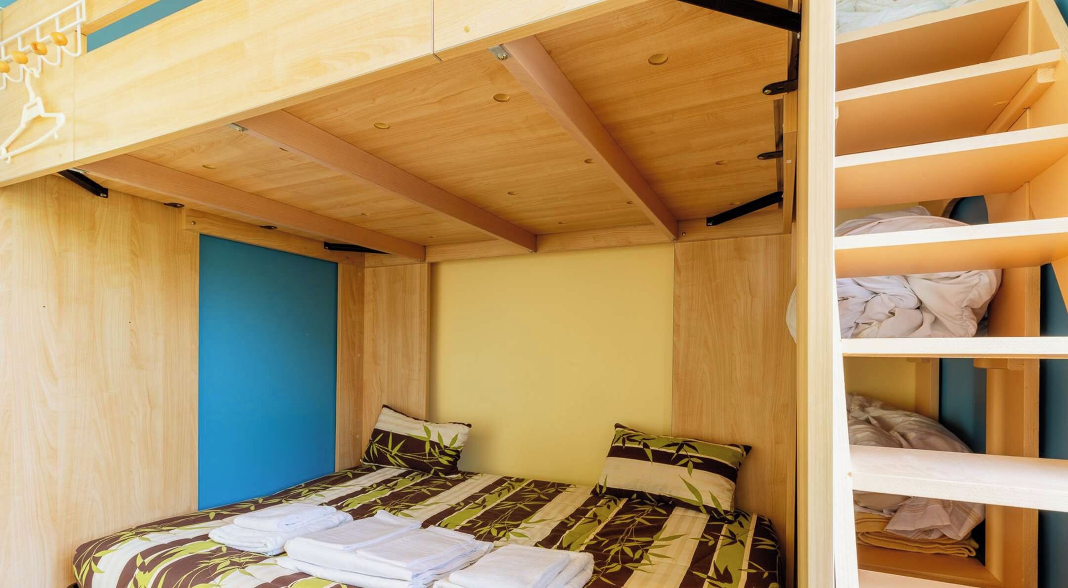 A compact room with a bunk bed, a single bed, and a wardrobe.