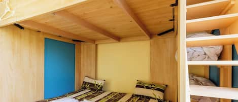 A compact room with a bunk bed, a single bed, and a wardrobe.