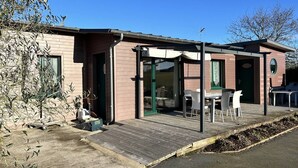 A modern house with a covered patio, a small outdoor kitchen, and a garden area. - South-facing chalet in Erquy | 8 guests | Ref 759 (ERQUY)