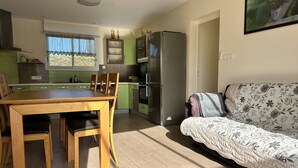 A compact living space with a dining area, kitchenette, and a sofa. - South-facing chalet in Erquy | 8 guests | Ref 759 (ERQUY)