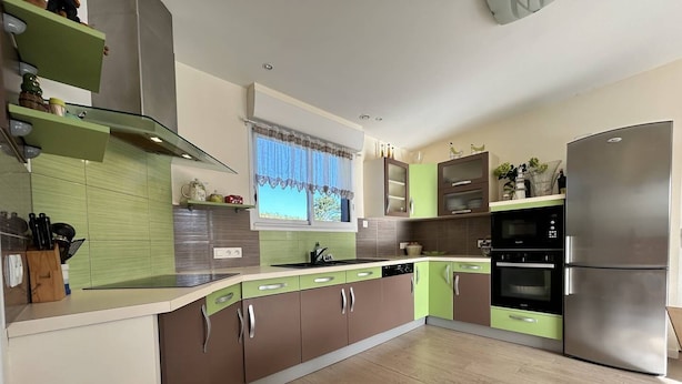 A modern kitchen with green and brown cabinetry, a stainless steel refrigerator, and a window with a view. - South-facing chalet in Erquy | 8 guests | Ref 759 (ERQUY)