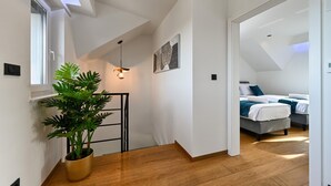 A modern, well-lit hallway leading to a bedroom with a bed, a potted plant, and a wall-mounted light fixture. - Lovely home in Vinogradi Ludbreski with sauna (Vinogradi Ludbreski)