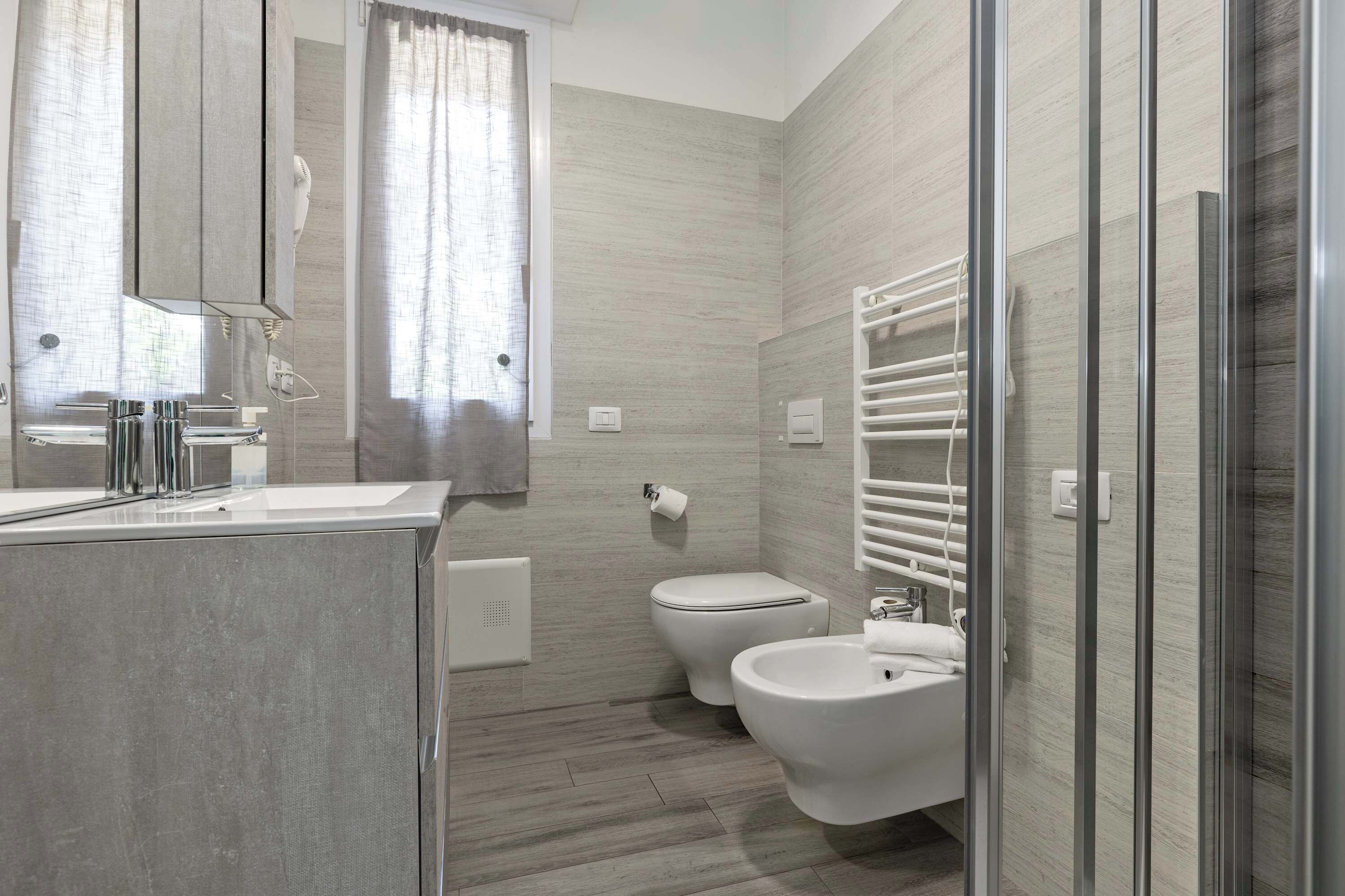 Une salle de bain moderne équipée d’une douche, de toilettes, d’un bidet et d’un grand miroir.