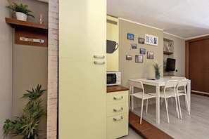 A compact living space with a kitchenette, a dining area with a table and chairs, and a wall adorned with framed pictures.