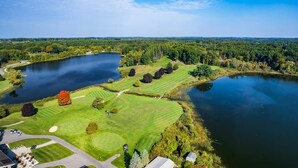 Ilmakuva golfkentästä, jossa on useita lampia, ja jota ympäröivät tiheät metsät ja kirkas taivas.