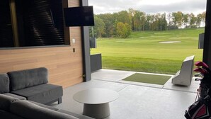Moderni olohuone, jossa on suuri ikkuna, josta avautuu näkymä golfkentälle.