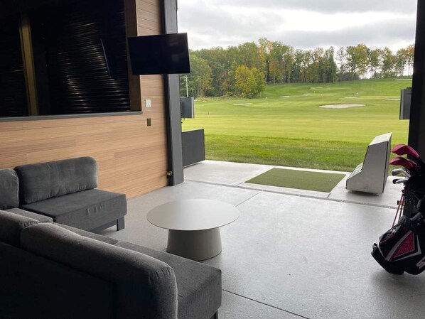 A modern living room with a large window overlooking a golf course.