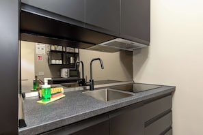 A modern kitchen with a double sink, stainless steel countertops, and a built-in range hood. - Civico 13 - Immobili e Soluzioni Rent (Bergamo)