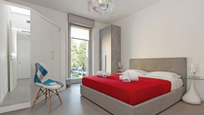 Un dormitorio moderno con una cama, una silla y vistas al exterior.