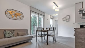 Una sala de estar moderna con sofá, mesa de comedor, sillas y un mapa del mundo en la pared.