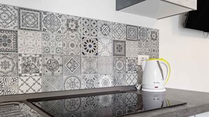 Una cocina con una placa de inducción moderna y una cafetera blanca sobre la encimera.