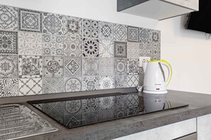 A kitchen with a modern induction cooktop and a white coffee maker on the counter. - Vivaldi Home - Immobili e Soluzioni Rent (Bergamo)