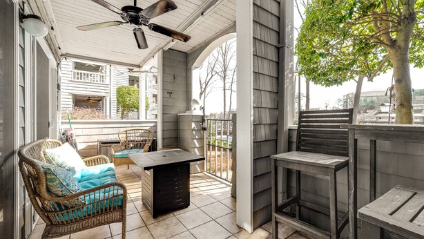A covered patio with wicker furniture, a table, and a ceiling fan. - Quaint and Cozy Lake Norman Condo Lakefront Walkable Dogs Ok (Davidson)