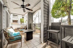 A covered patio with wicker furniture, a table, and a ceiling fan.