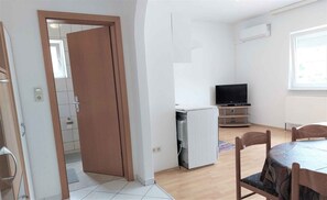 Cozy living space with a dining area, TV, and radiator under a window.
