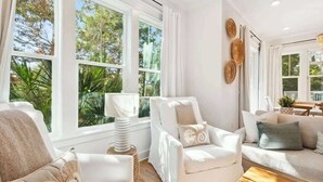 A room with large windows, a white sofa, a chair, and a lamp.