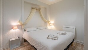 Ein Schlafzimmer mit Himmelbett, Nachttischlampen und ordentlich gefalteten Handtüchern.