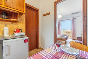 A kitchen with wooden cabinets, a refrigerator, and a dining area with a table set for two.